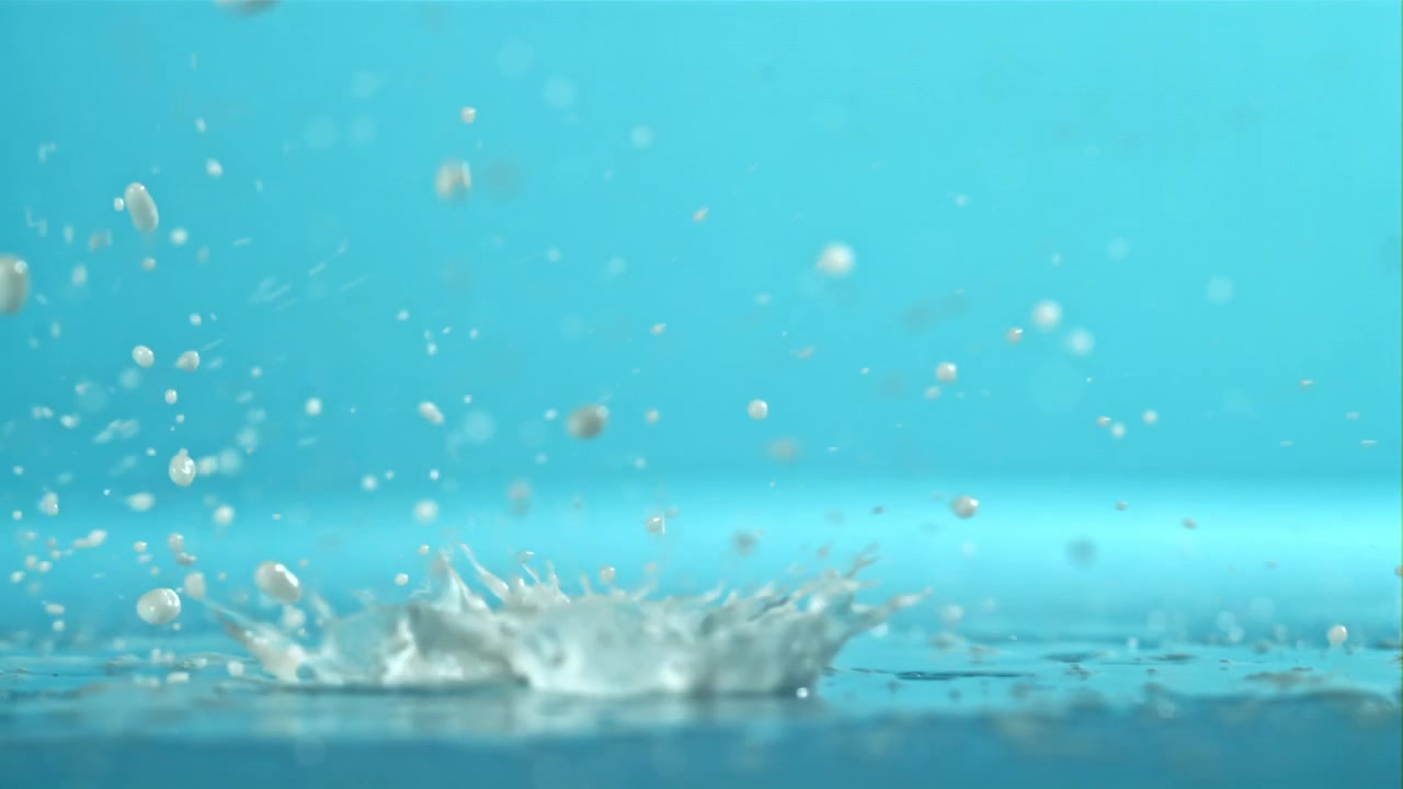 Slow Motion White Liquid Drops Splashing on a Blue Surface