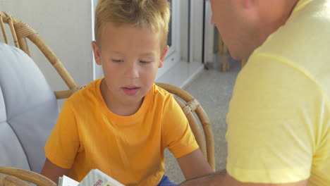 Child-and-father-reading-book-on-the-balcony