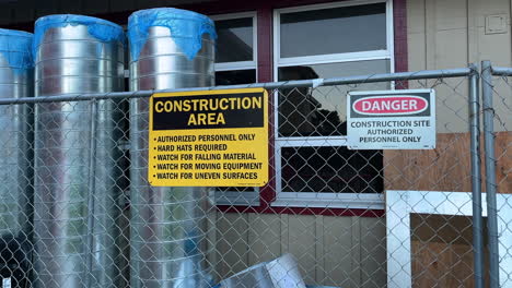 new unused stainless steel water tanks behind wire mesh fence with construction area warning signs