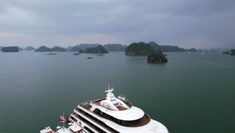 aerial flying over white luxury mega yacht in ha long bay vietnam on cloudy day