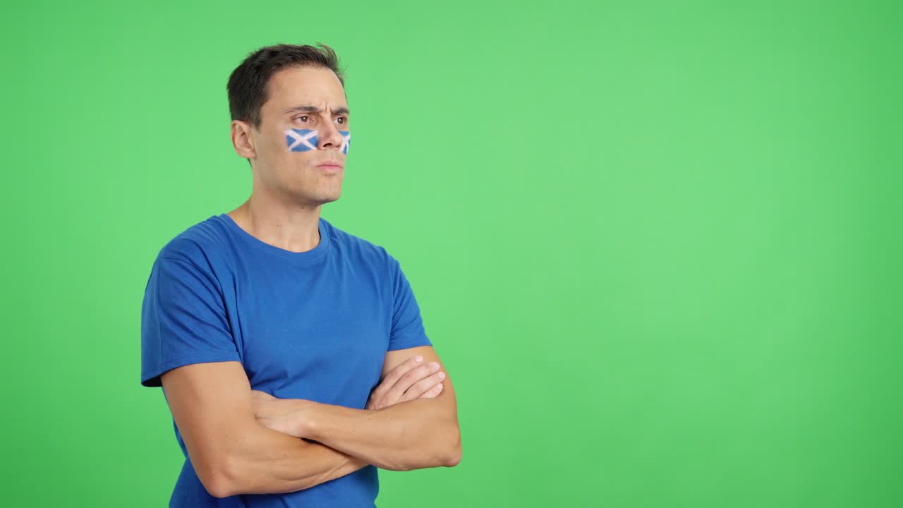 Man with scottish flag painted looking away with serious expression