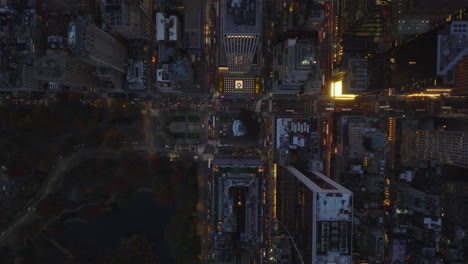 Vista-Aérea-De-Pájaros-Vista-De-Arriba-Hacia-Abajo-Del-Tráfico-Nocturno-En-La-Ciudad.-Carreteras-Transitadas-Entre-Bloques-De-Edificios-De-Gran-Altura.-Manhattan,-Ciudad-De-Nueva-York,-Estados-Unidos