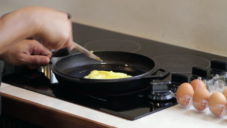 man fries and flips egg omelet in cast iron skillet