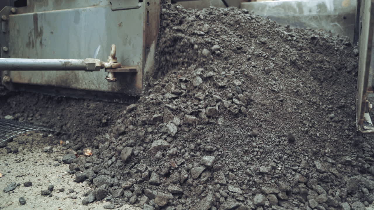 Process of pouring hot asphalt out off the heavy machine into the ground. Roadworks repaving process. Close-up