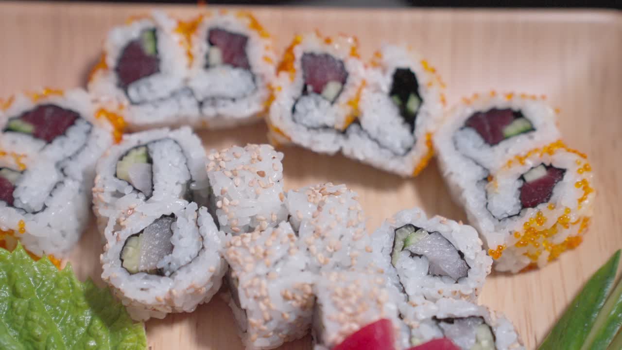 A drop-down shot showcases a decorative plate filled with a variety of sushi, highlighting the vibrant colors and intricate presentation. Perfect for culinary, sushi, and food content.