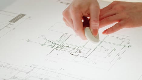 hands erasing a blueprint