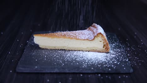 verser du sucre sur une tranche de gâteau au fromage sur une plaque de pierre gros plan tirer au ralenti