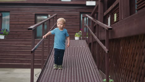 Lovely-child-goes-down-wooden-wheelchair-ramp-near-veranda