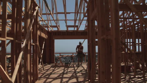 a contractor carries a piece of wood in an unfinished home