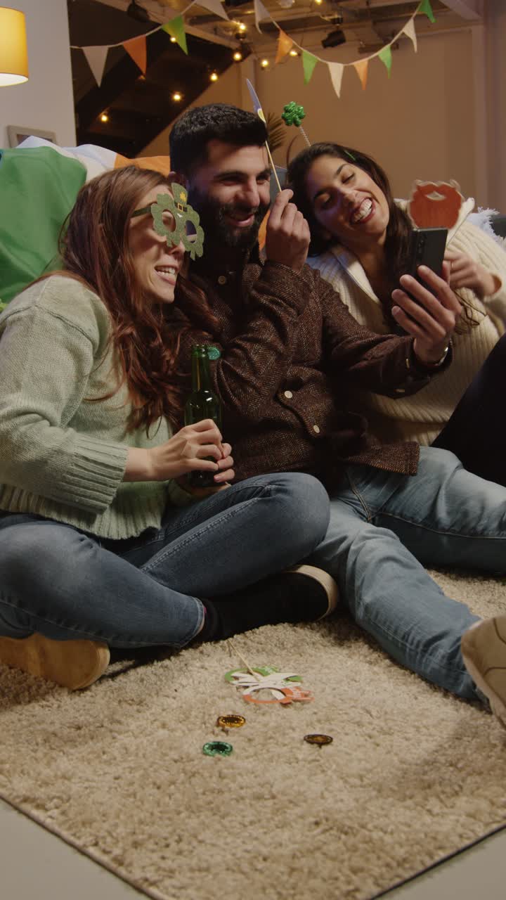 video verticale di amici che si vestono a casa per festeggiare la festa del giorno di san patrizio facendo una videochiamata sul cellulare 2
