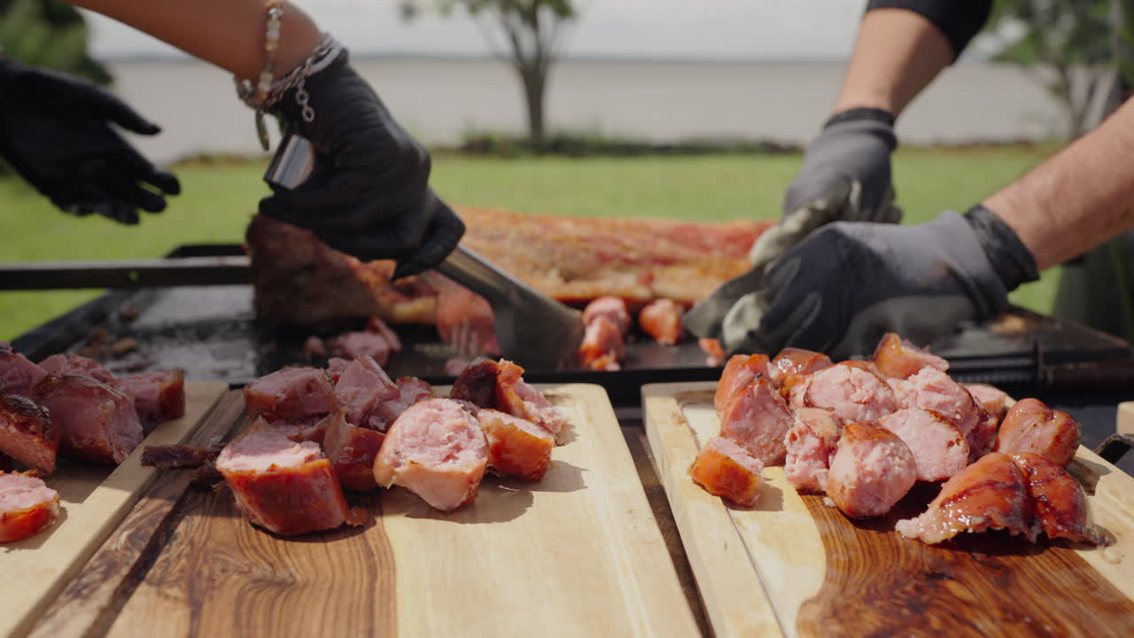 Chef slicing grilled meat and sausages on wooden board during traditional Argentinian asado