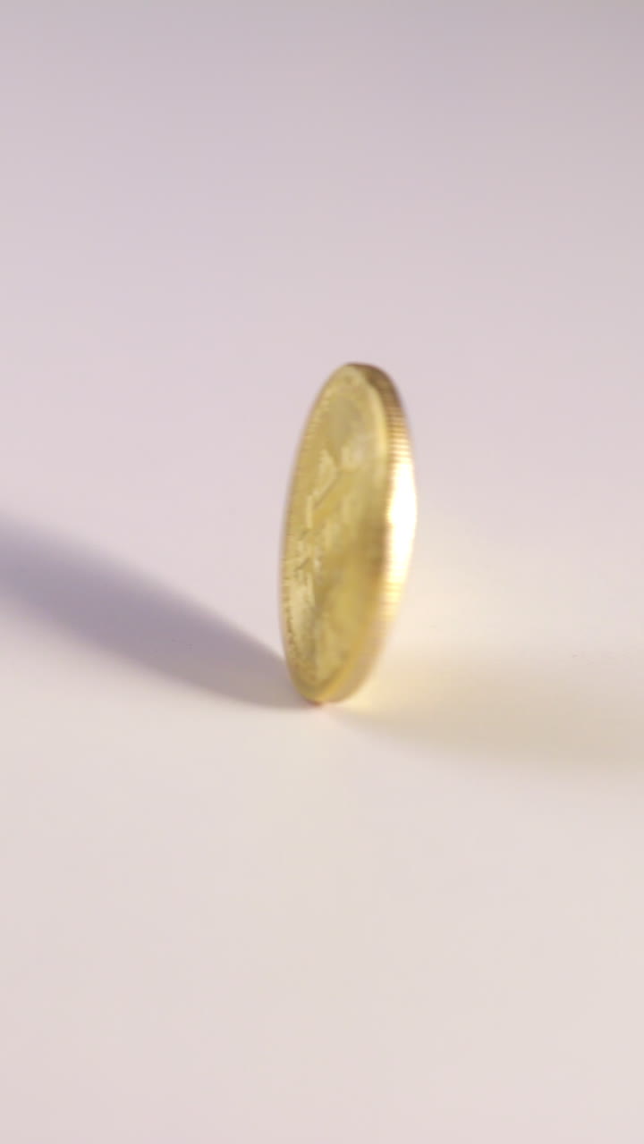 A gold Bitcoin rotates upright in slow motion on a smooth white surface, emphasizing reflective textures, detailed engravings, and the iconic cryptocurrency logo in a seamless spin.