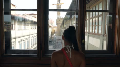 woman looking at the city view from a window in florence, italy