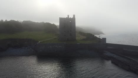 Drone-Moviéndose-Hacia-El-Mar-Y-Hacia-La-Niebla-En-Carrigaholt-Castle-Irelands-Cost-Casa-Torre-Embrujada