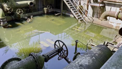 una gran tubería vieja y oxidada se encuentra en el agua en una fábrica de acero industrial abandonada en duisbrug landschaftspark alemania