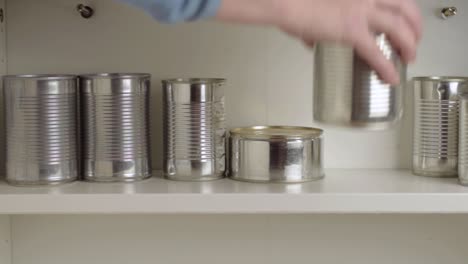 stacking aluminum tin cans in a food cupboard shelf