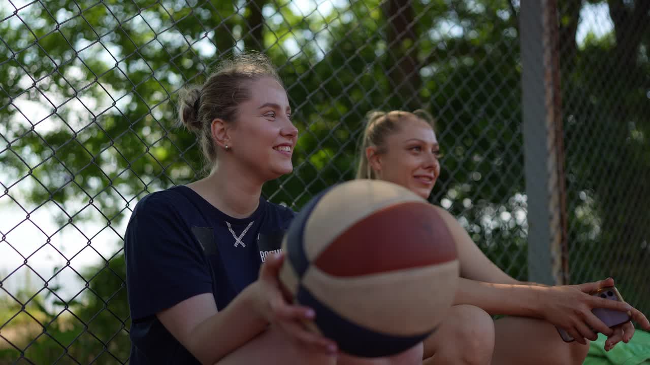 두 명의 여성이 농구장에서 휴식을 취하고 있습니다.