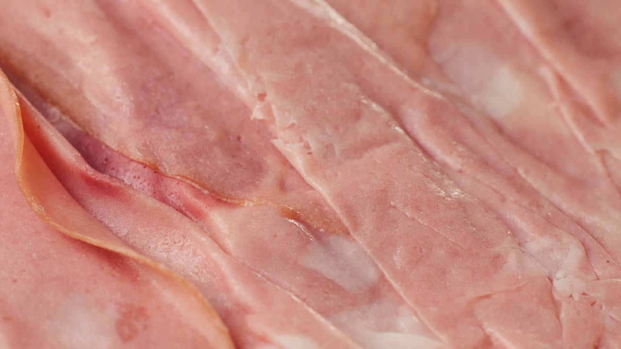 Ham italian mordatella, man Slices Of Traditional Italian antipasti mortadella sausage on a wooden cutting board, close up macro of chicken or turkey jamon, fat breakfast dish.
