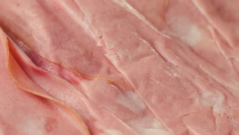 ham italian mordatella, man slices of traditional italian antipasti mortadella sausage on a wooden cutting board, close up macro of chicken or turkey jamon, fat breakfast dish.