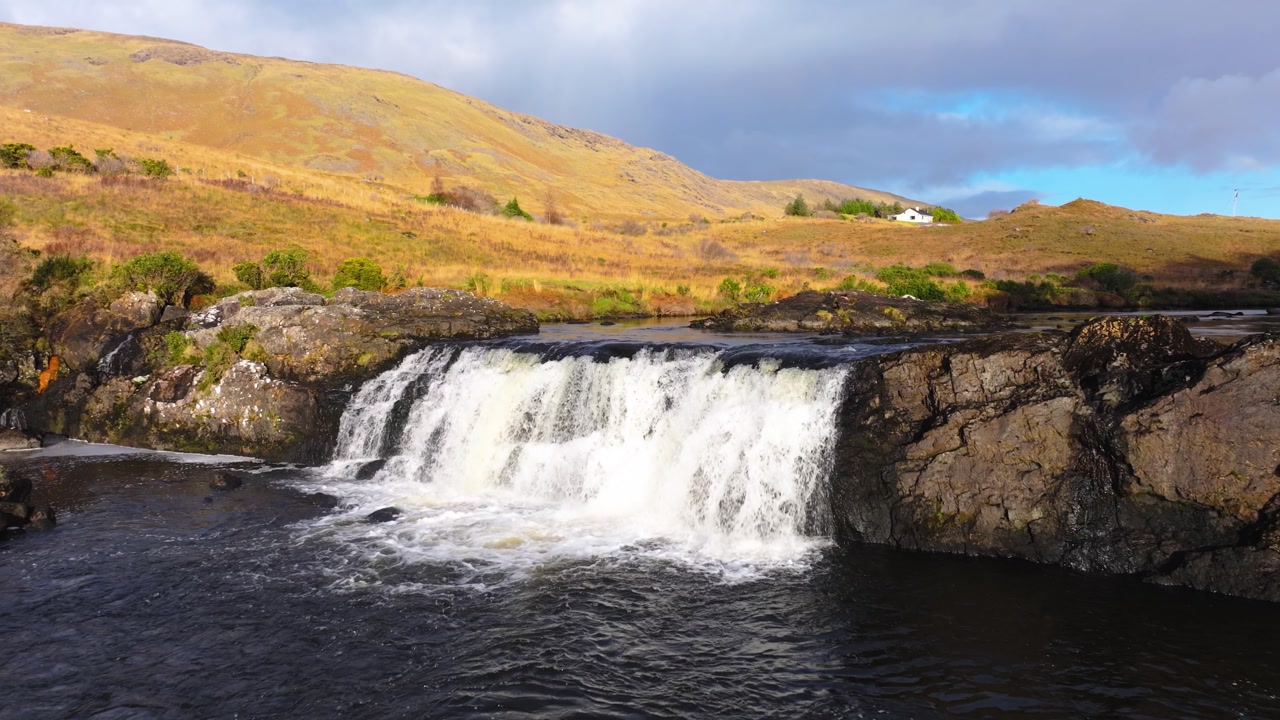 4K Aerial view of Aasleagh Falls highlighting a small waterfall along a river in a remote natural setting. Captures the movement of water and surround._11