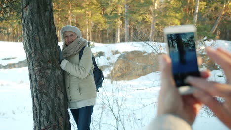 senior woman taking a picture in a snowy forest
