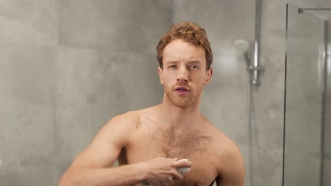 hombre atlético con el torso desnudo usa spray antitranspirante