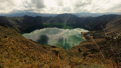 quilotoa lagoon water filled crater lake ecuador andes volcano aerial time lapse of crystalline water, andean cordillera and clouds movement