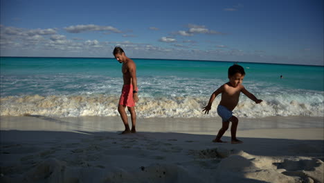 Joven-Moreno-Latino-Mexicano-Huyendo-De-Las-Olas-Con-Su-Padre-En-Una-Playa-En-Cancún-México