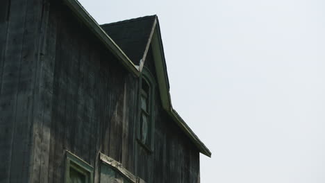 wind blows open broken window of eerie creepy abandoned burnt dark wood building