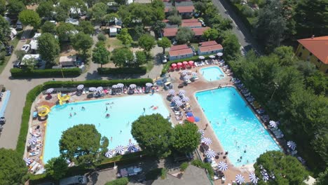 aerial shot orbiting swimming pool with people in camping cisano san vito at lake garda, italy