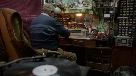 vinyl record spins by elderly man handling old radio equipment, static