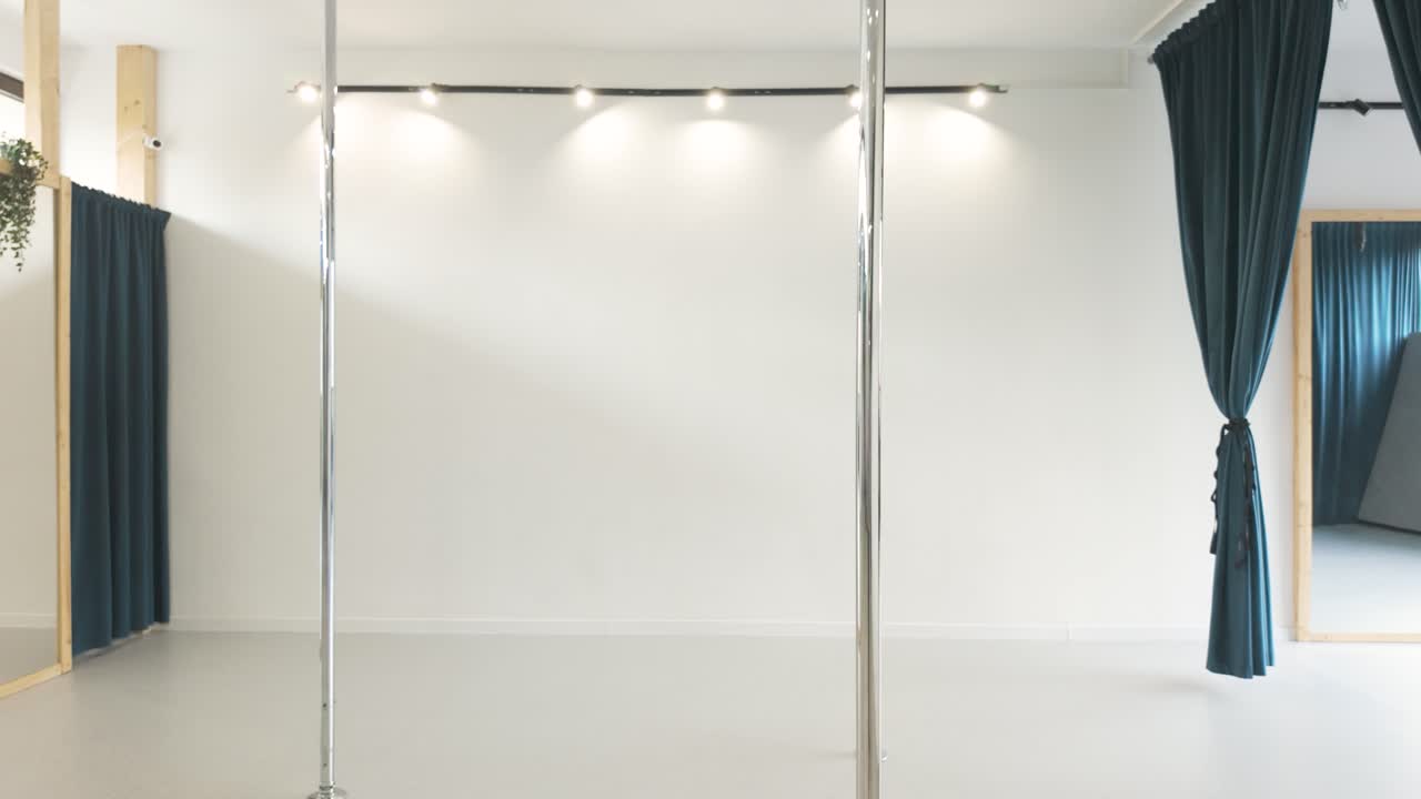 Agile girl doing acrobatic tricks on a pole dance bar