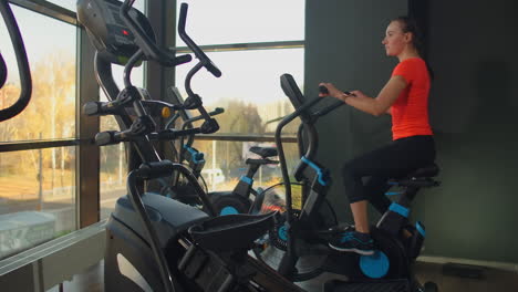 young active woman spinning a air bike in gym with trainers. female training on air bike