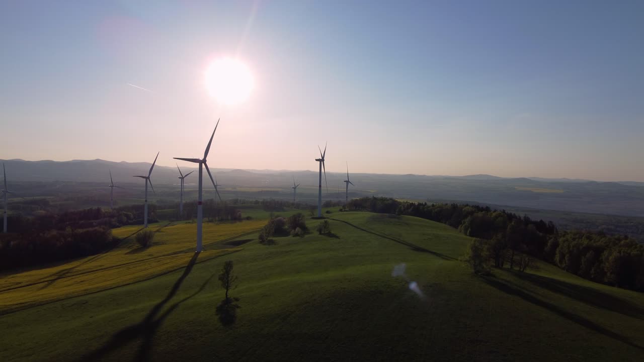 Drone view flies to windmills group before sunset, spring colors, propeller shadows
