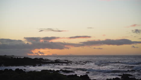 Calm-serene-sunset-with-waves-rushing-toward-rocky-beach-at-sunset