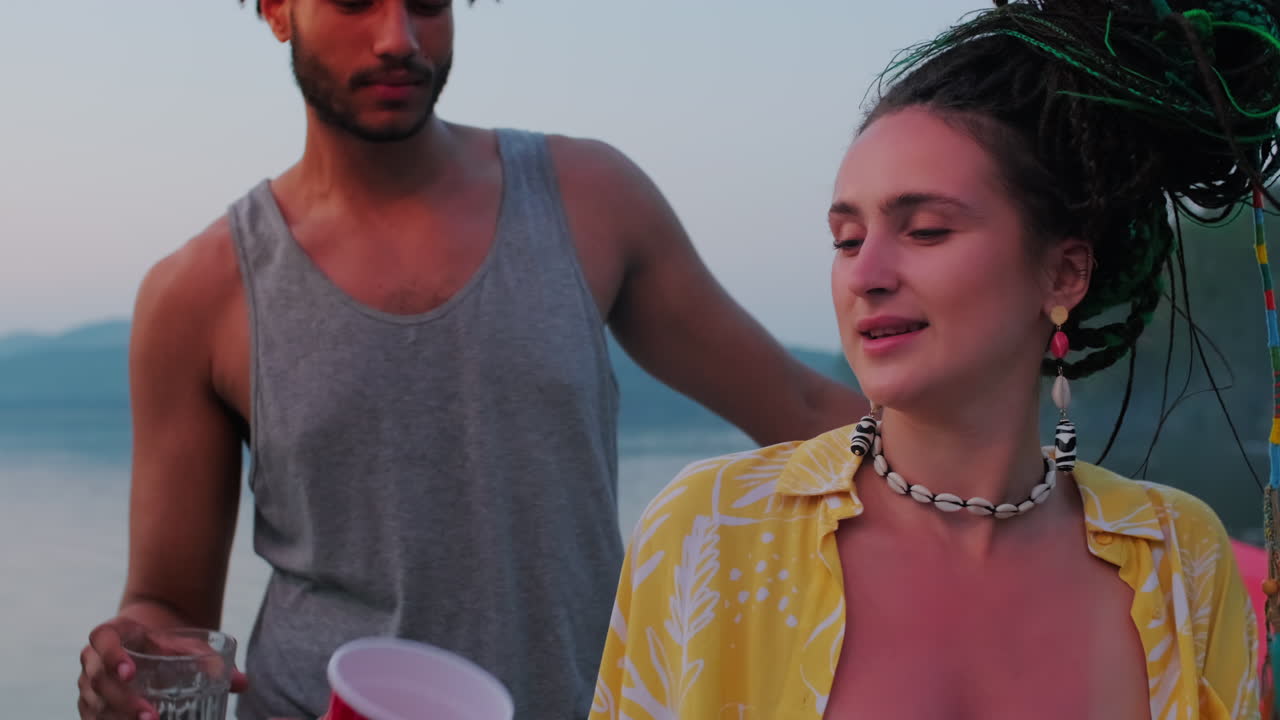 молодая женщина танцует с друзьями-мужчинами на вечеринке на озере.