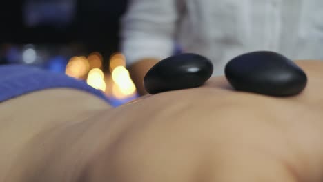 masseuse puts hot therapy stones on woman's back in slow motion