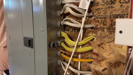 wires going into electrical panel in unfinished basement mounted on pressboard