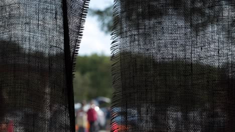 close-up view of a black sheer curtain with people and trees visible through it