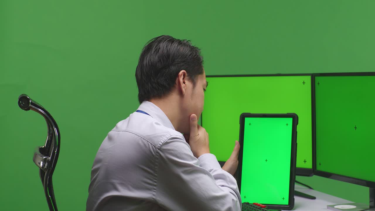 다중 모니터 앞에서 태블릿을 사용하는 사업가