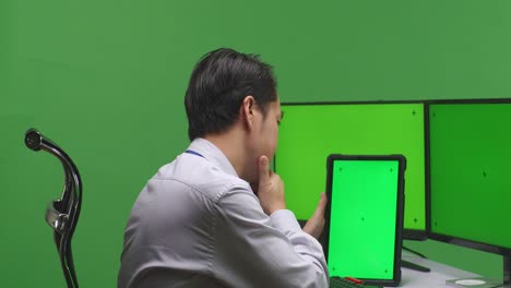 hombre de negocios usando tableta frente a múltiples monitores