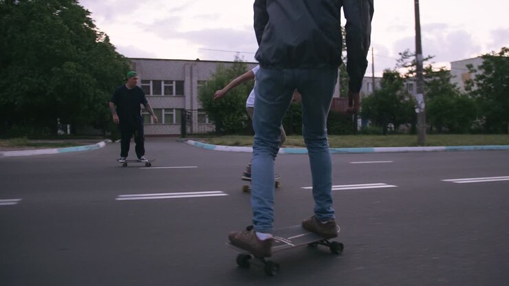 Gruppo di giovani che fanno skateboard sulla strada al mattino presto, ripresa cinematografica, slow motion.