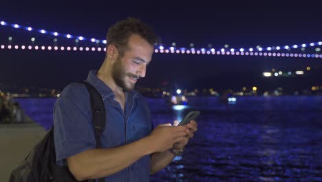 young man using phone at night. seashore.