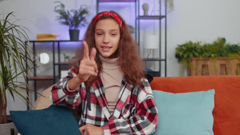 preteen girl smiling, pointing to camera, choosing lucky winner, indicating inviting approve at home