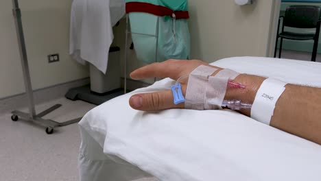 movimientos lentos de la mano de la mano derecha masculina caucásica irreconocible en un escenario médico con iv en la muñeca