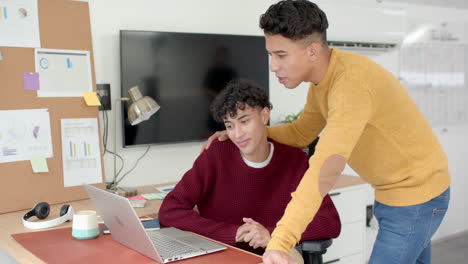 Using laptop, multiracial gay couple collaborating on project in home office setting
