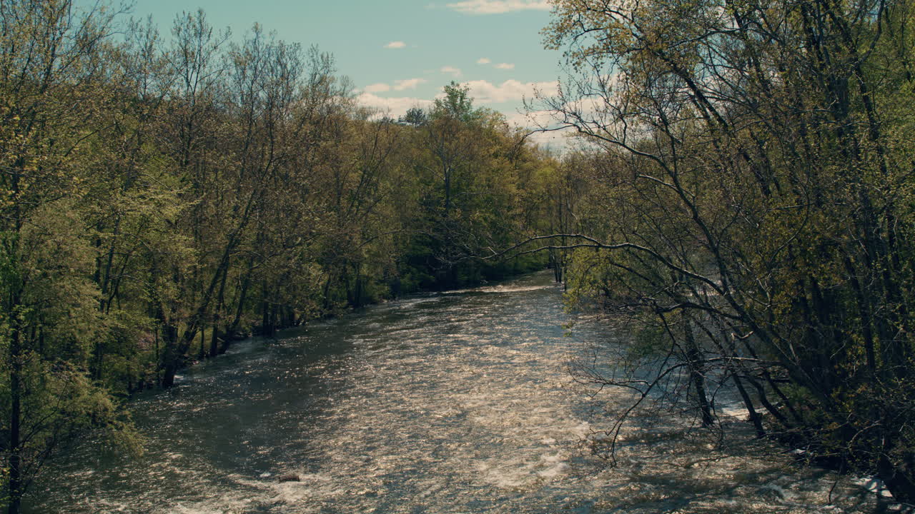 wide shot of croton river flowing away from camera with beautiful afternoon fun reflections in water and blue skies in the summer. Slow motion 40fps