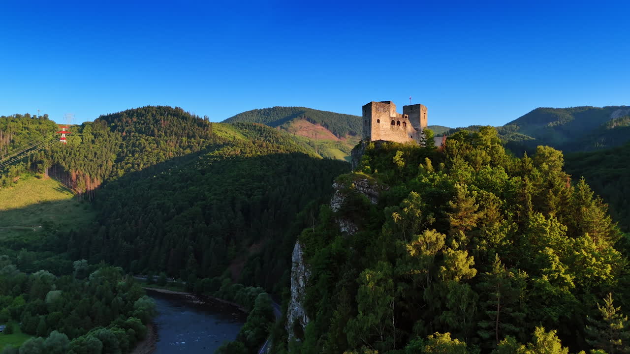 Approaching the walls of the castle on the high rock. Narrow river flows at the foot. Stunning Tatra mountains covered with woods around. Slovakia