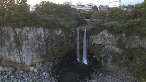 drone aerial view in south korea flying in front of a waterfall over the sea rocky area approach jeju island