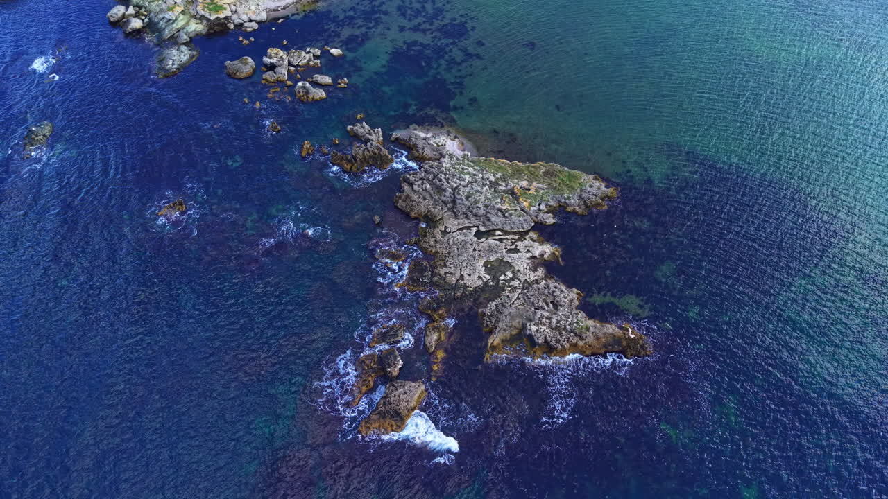 Majestic rocky coastline reveals hidden treasures beneath clear blue waters at sunrise in a tranquil seaside escape